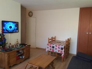 - un salon avec une table et une télévision murale dans l'établissement Le Plazza, à Valberg