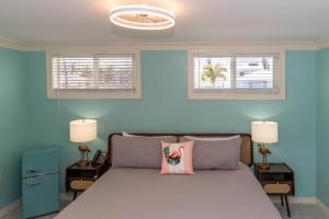ein Schlafzimmer mit einem Bett mit blauen Wänden und zwei Fenstern in der Unterkunft Flamingo Inn in Fort Myers Beach
