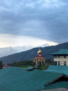 a temple on top of a building with mountains in the background at Hotel khangyul in Ravangla