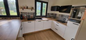 a kitchen with white cabinets and a sink and windows at quiet house in Nogent-sur-Eure