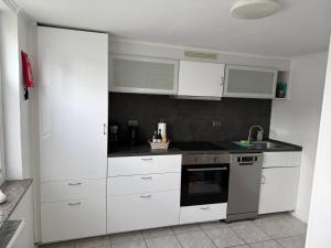 a kitchen with white cabinets and a stove top oven at Ferienapartment Stemmert in Gelting +1 photo