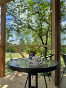 a table with a cup and a vase with flowers on it at Babitouli-2 in Niabauri +34 photos