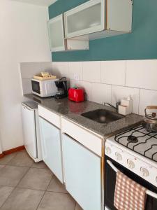 a small kitchen with a stove and a sink at Camiare Aparts in Villa General Belgrano