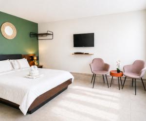 a bedroom with a bed and two chairs and a tv at Le P'tit Rubis in Le Tampon