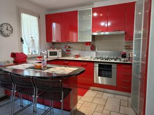 a kitchen with red cabinets and a kitchen island with bar stools at Casina Rossa in Ballabio