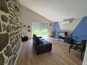 a living room with a couch and a tv at La maison vigneronne in Polignac