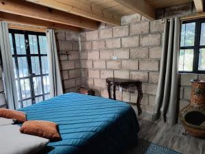 a bedroom with a blue bed and a brick wall at Cabaña Metztli in Amealco +8 photos