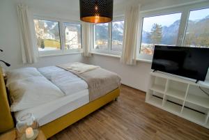 a bedroom with a bed and a flat screen tv at Dangos Mountainview Gosau in Gosau
