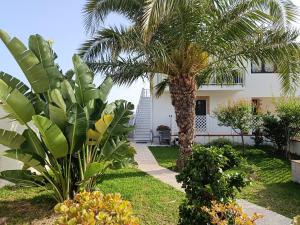 a garden with two palm trees in front of a house at Appartamento - Plemmirio - Villa Maria Serena in Syracuse