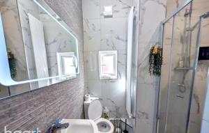 a bathroom with a toilet and a glass shower at Sunshine apartment in Maidstone