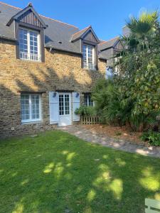 a brick house with white doors and a yard at La Petite Bergère in Saint-Méloir-des-Ondes