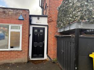 a brick building with a black door and a window at Sunshine apartment in Maidstone