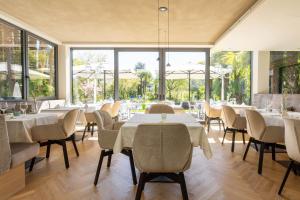 ein Restaurant mit Tischen und Stühlen und großen Fenstern in der Unterkunft Hotel Gschwangut in Lana