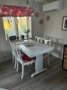 a white dining room table with white chairs and a chandelier at Lillhuset Gallerud in Årjäng