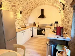 a kitchen with white cabinets and a stone wall at Le jardin de Grignan in Réauville