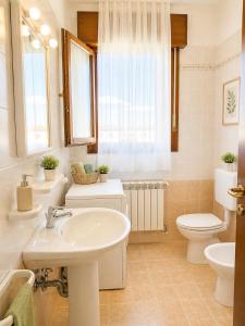 a white bathroom with a sink and a toilet at Residence Mediterraneo - Agenzia Cocal in Caorle +30 photos