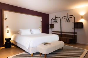ein Schlafzimmer mit einem großen weißen Bett und einem Hocker in der Unterkunft Hotel 2M, The Originals Relais in Saint-Rambert-sur-Loire + 22 Fotos