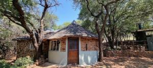 a small stone house with a thatched roof at Shala Mushe Tented Camp & Camp in Warmbaths