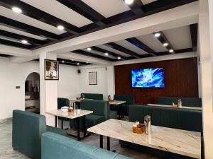 a restaurant with tables and chairs and a flat screen tv at Hotel khangyul in Ravangla
