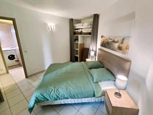 a bedroom with a bed with a green comforter at Barcaresa - Malibu village Catalan T2 terrasse in Canet-en-Roussillon +22 photos
