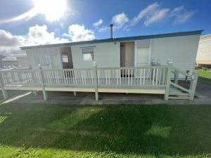 a white house with a porch and a white fence at GnT Caravan lets in Anderby