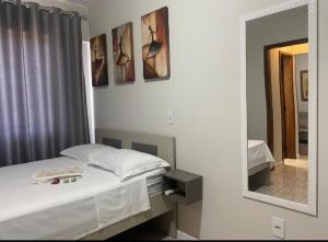 a bedroom with a white bed and a mirror at Loft aconchegante no Centro in Joinville