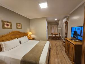 a hotel room with a bed and a flat screen tv at Pousada Villaggio Itália in Campos do Jordão