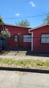 a red building with a fence in front of it at Cabaña La Petita in Cherquenco