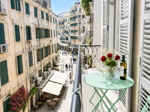 a balcony with a table and flowers on a street at Veneziana Liston view apt in Corfu