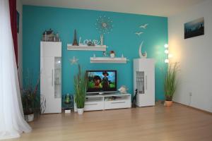 a living room with a tv and a blue wall at Ferienhaus Victoria in Norden