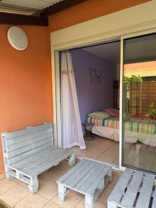 a porch with a bench and a room with a bed at Kaz'Baduel piscine, terrasse, wifi et climatisation in Cayenne