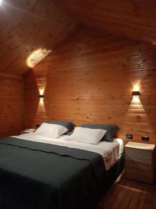 a large bed in a wooden room with two lights at Glamping villeta campo heliconias in Villeta