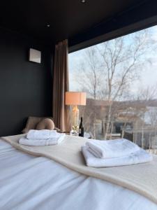 a bed with towels on it with a window at Aurora Sea Lodges in Karpbukt