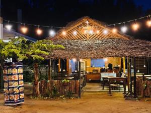 a restaurant with a straw roof with lights on it at Baywatch Arugambay in Arugam Bay