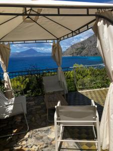 a patio with chairs and an umbrella and the ocean at Villa Torre in Acquafredda