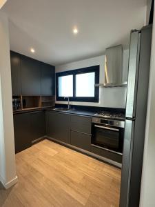 a kitchen with black cabinets and a stainless steel refrigerator at Concepto Home in Rafaela