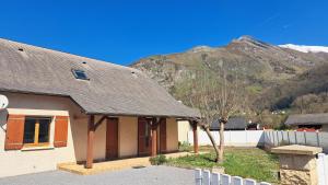 a house with a tree in front of a mountain at L'évasion Monplaisir in Gère-Belesten