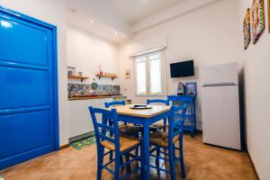 eine Küche mit blauen Stühlen, einem Tisch und einem Kühlschrank in der Unterkunft A Patedda in Favignana