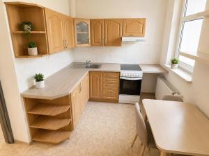 a small kitchen with wooden cabinets and a table at Moderní studio s terasou v klidné lokalitě in Jihlava