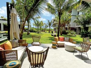 a patio with chairs and furniture and palm trees at Tropical - Resort - Spa - Pool & Garden in Grand-Baie