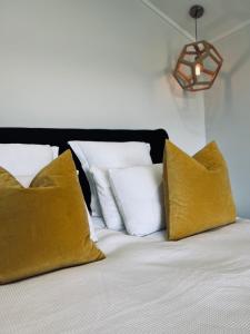 a bed with yellow and white pillows on it at Coco's Bungalow in Mudgee