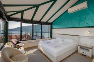 a bedroom with a bed and a chair and windows at Guesthouse Villa Stari Grad in Herceg-Novi