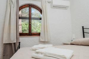 a bedroom with a window with towels on a bed at Casa P - Relax nel verde a Ezzi Minori in Cuile Ezi Mannu