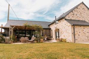 a brick house with a patio and a yard at Villa vue Mer- grand jardin -cuisine d'été- 4 chambres- Vidéo projecteur in Planguenoual