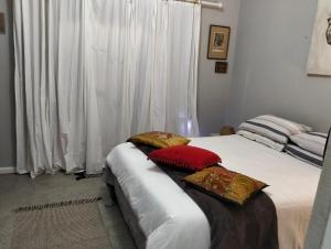 two beds in a room with white curtains and red pillows at The Hidden Corner in Sedgefield