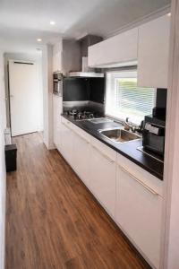 a kitchen with white cabinets and a wooden floor at 't Vrolijke Uusje in Scharendijke