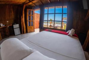 a large bed in a room with a large window at Cocoa Beachfront Inn in Canoa