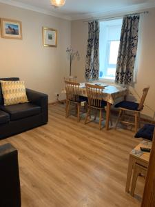 a living room with a couch and a table and chairs at Sineag's Cottage in Pollachar