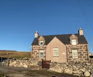 a brick house with a stone wall at Sineag's Cottage in Pollachar +21 photos