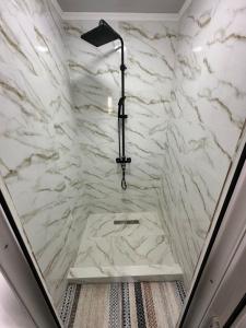 a shower with a white marble wall at Gulazyk guest house in Bokonbayevo